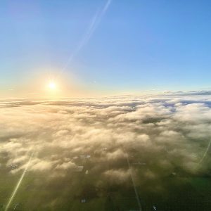 Hot air balloon flying over the clouds in front of Mt. Rainier
